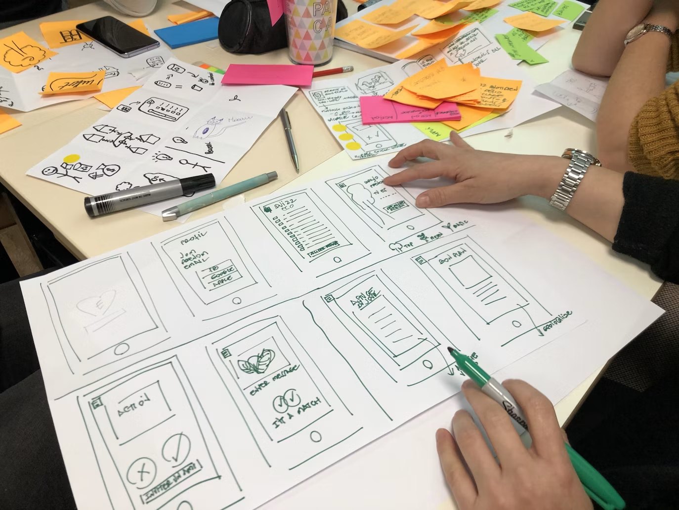 Hand-drawn product screen sketches on a workshop table